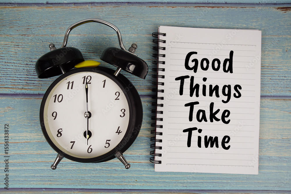 Poster good things take time text written on notepad with alarm clock on wooden background