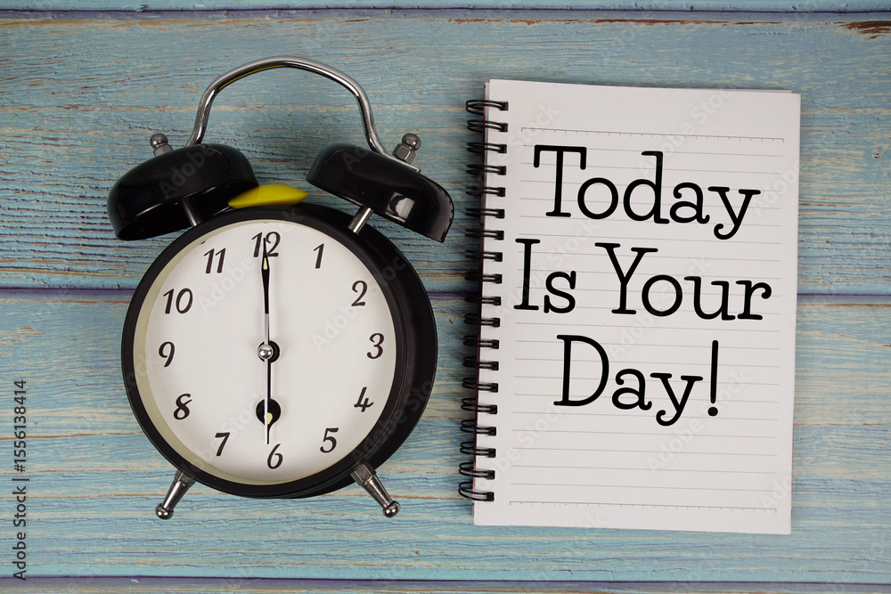 Poster today is your day! text written on notepad with alarm clock on wooden background
