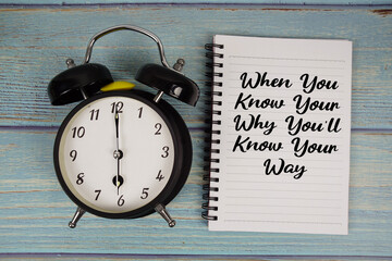 When You Know Your Why You'll Know Your Way text written on notepad with alarm clock on wooden...