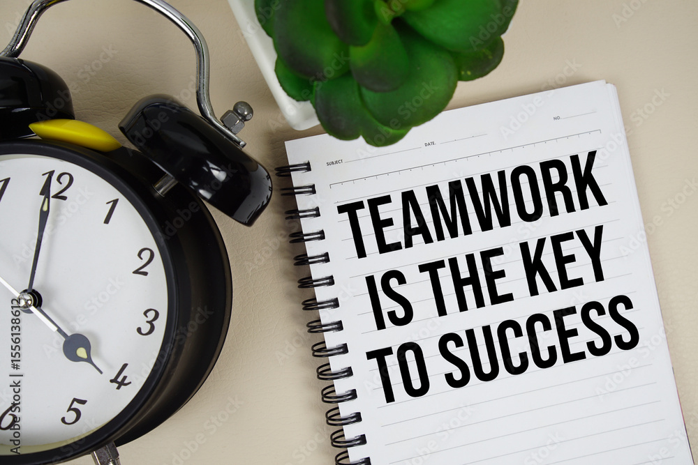 Poster teamwork is the key to success text written on notepad with alarm clock