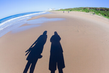 Man Woman Walking Beach Sand Shadows Reflections Ocean Coastline Landscape