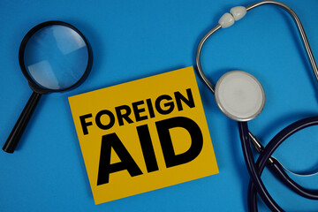 Foreign Aid  text with Stethoscope and magnifying glass on blue background