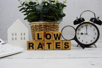 LOW RATES alphabet letters with house model, alarm clock and magnifying glass on wooden background