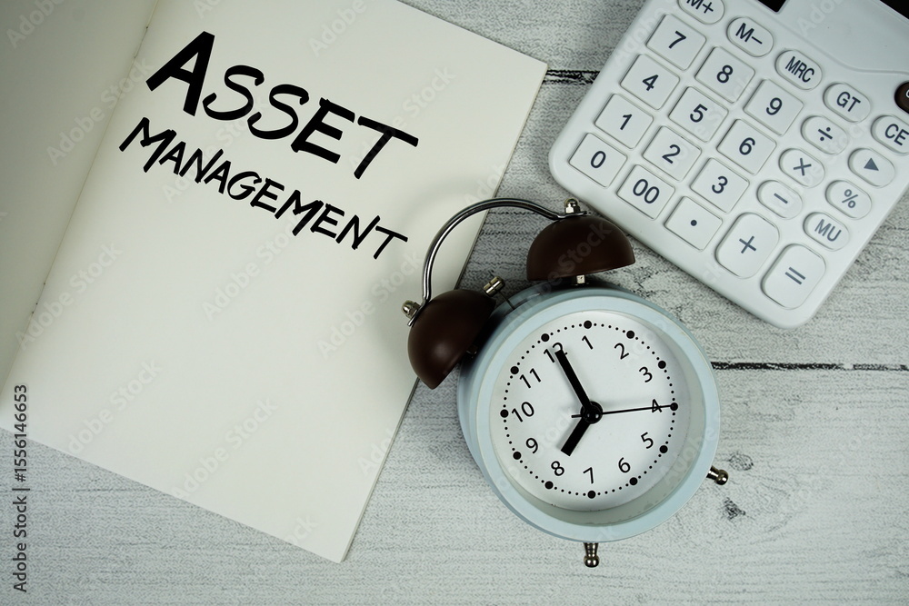 Aufkleber asset management text on paper notebook page with alarm clock and calculator on wooden background
