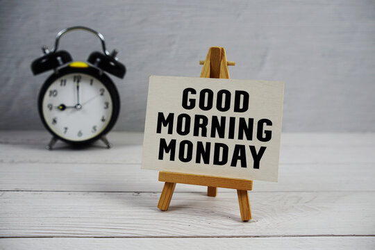 Good Morning Monday text with easel and alarm clock on wooden background