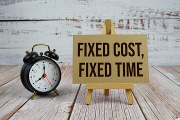 Fixed Cost, Fixed Time text with easel and alarm clock on wooden background