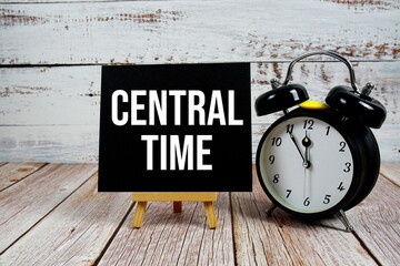 Central Time text with easel and alarm clock on wooden background