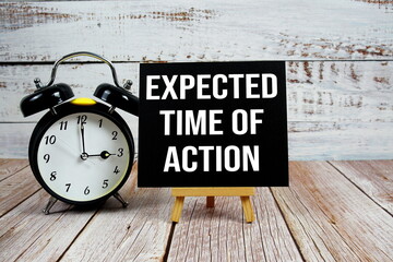 Expected Time Of Action text with easel and alarm clock on wooden background