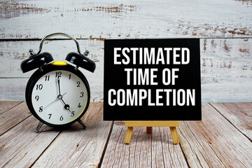 Estimated Time Of Completion text with easel and alarm clock on wooden background