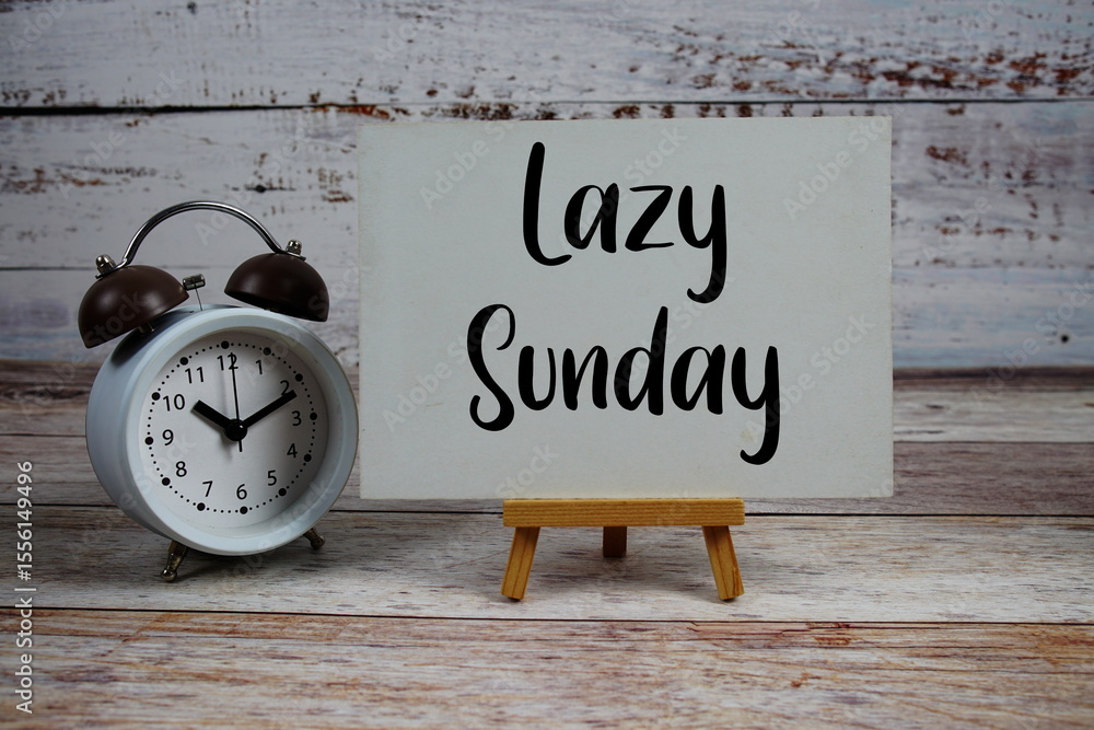 Poster lazy sunday text with easel and alarm clock on wooden background