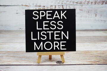 Speak Less Listen More text with easel on wooden background
