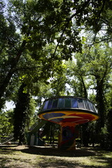 Unusual round building resembling a flying saucer located in a lush green summer forest. Sunlight...