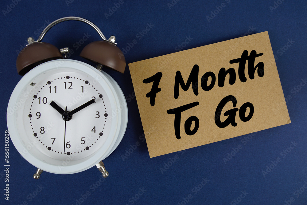Poster 7 month to go text written on paper with alarm clock on blue background