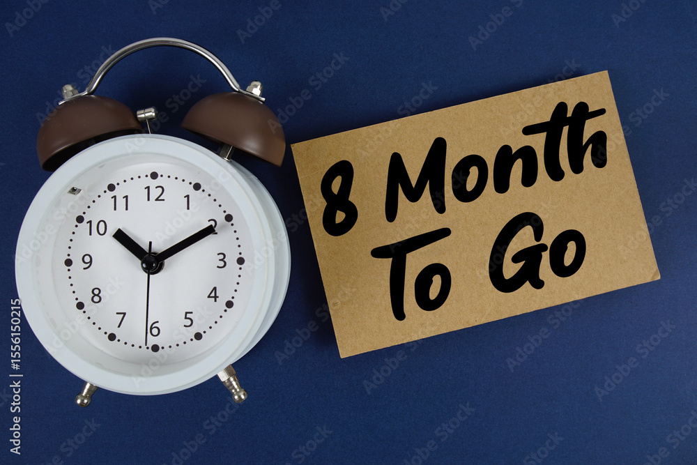 Poster 8 month to go text written on paper with alarm clock on blue background