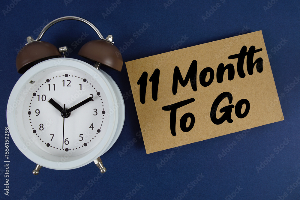 Poster 11 month to go text written on paper with alarm clock on blue background