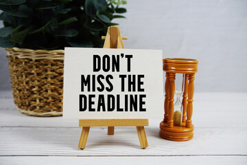 Don't Miss The Deadline text with hourglass on wooden background