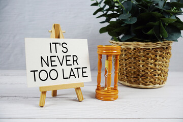 It's Never Too Late text with hourglass on wooden background