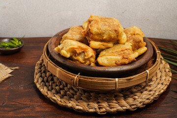 Traditional Indonesian fried tofu filled with vegetables, served on a woven bamboo tray. Crispy on the outside, savory and soft inside a beloved street food snack.