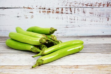 Fresh green long Thai eggplants on wooden background