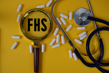 FHS abbreviation of Family Health Survey text on paper card with Stethoscope and magnifying glass...