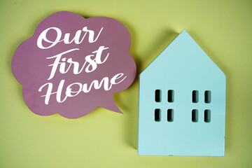 Our First Home text with house model on yellow background