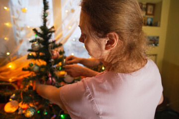 Woman decorates Christmas tree with ornaments in cozy living room during festive holiday season