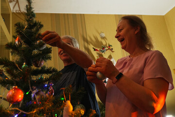 Couple decorating Christmas tree together in cozy living room during festive season