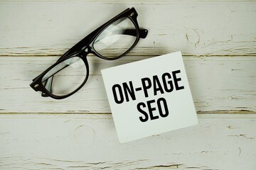 On-page SEO text message on paper with eyeglasses on wooden background