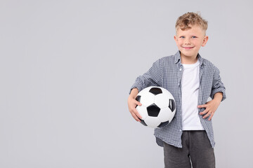 Little boy with soccer ball on gray background, space for text
