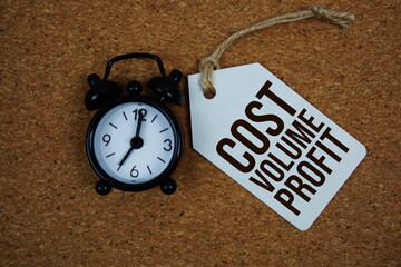 Cost Volume Profit text on price tag with alarm clock on cork board background