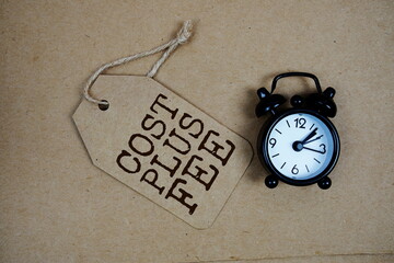 Cost Plus Fee text on price tag with alarm clock on paper craft background