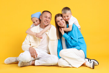 Full length portrait of happy family on yellow background