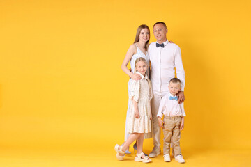 Full length portrait of happy family on yellow background. Space for text
