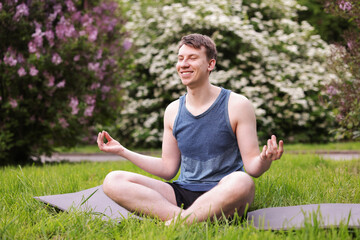 Young man practicing yoga on mat in park