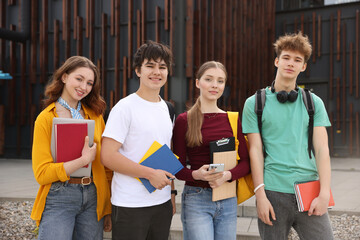 Group of teenagers with books near building outdoors