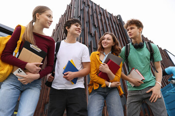 Group of happy teenagers near building outdoors, low angle view