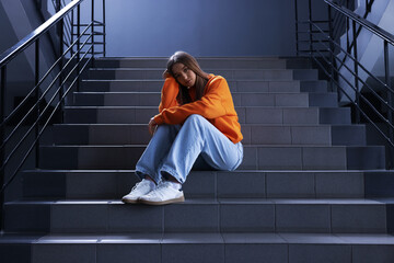 Bullying. Upset teenage girl on stairs indoors