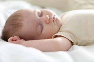 Cute newborn baby sleeping on bed indoors