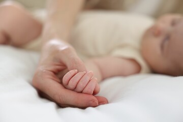 Mother with her newborn baby on bed indoors, closeup