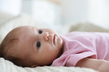 Cute newborn baby lying on bed indoors