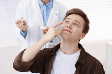 Young man putting on contact lenses in ophthalmologist office