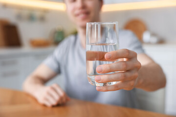 Man with glass of water in kitchen, selective focus