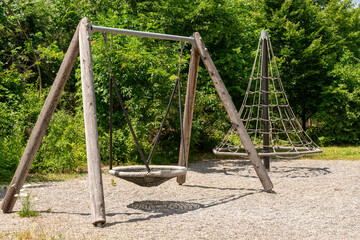Kids playground at a sunlit place with trees on one side. Playing structres are casting shadows on the ground.