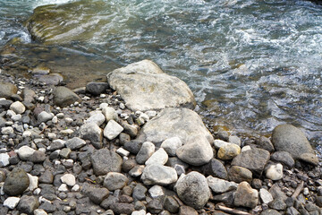 Clear water flowing gently beside a rocky riverbank with natural stone textures