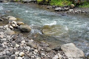 Clear water flowing gently beside a rocky riverbank with natural stone textures