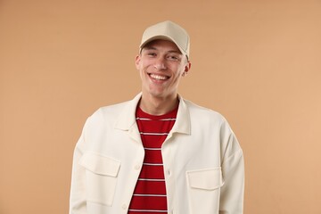 Young man in stylish baseball hat on beige background