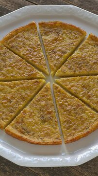 Socca or farinata - chickpea flour pancake with rosemary herb. Homemade traditional Italian cuisine dish cut into pieces. Table spin, vertical video.