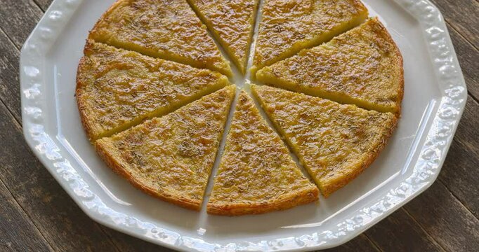 Socca or farinata - chickpea flour pancake with rosemary herb. Homemade traditional Italian cuisine dish cut into pieces. Table spin.