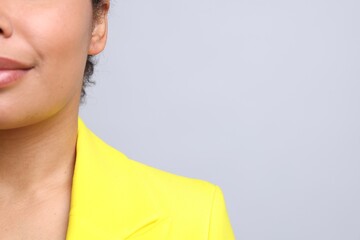 Young woman with pierced ear on light grey background, closeup. Space for text