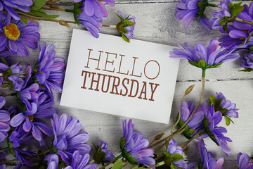 Hello Thursday text with flowers decoration on wooden background